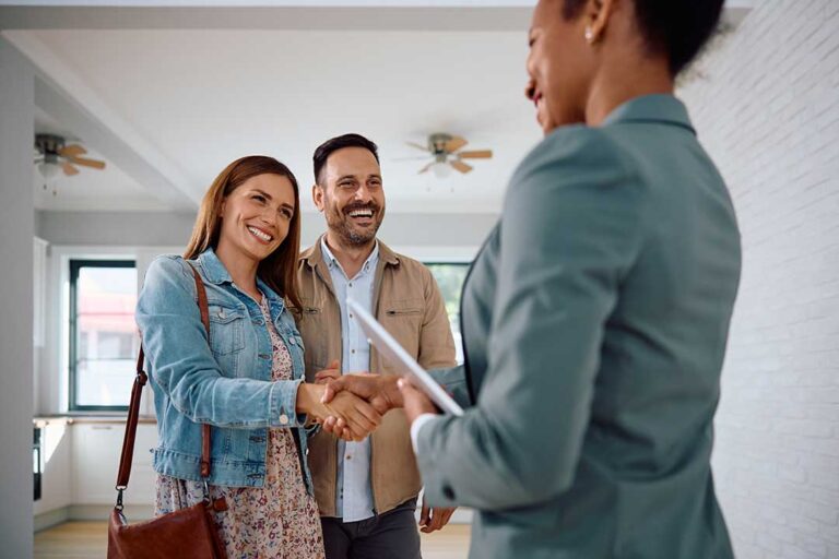 A couple reviews financial documents together at a kitchen table while considering a home purchase.
